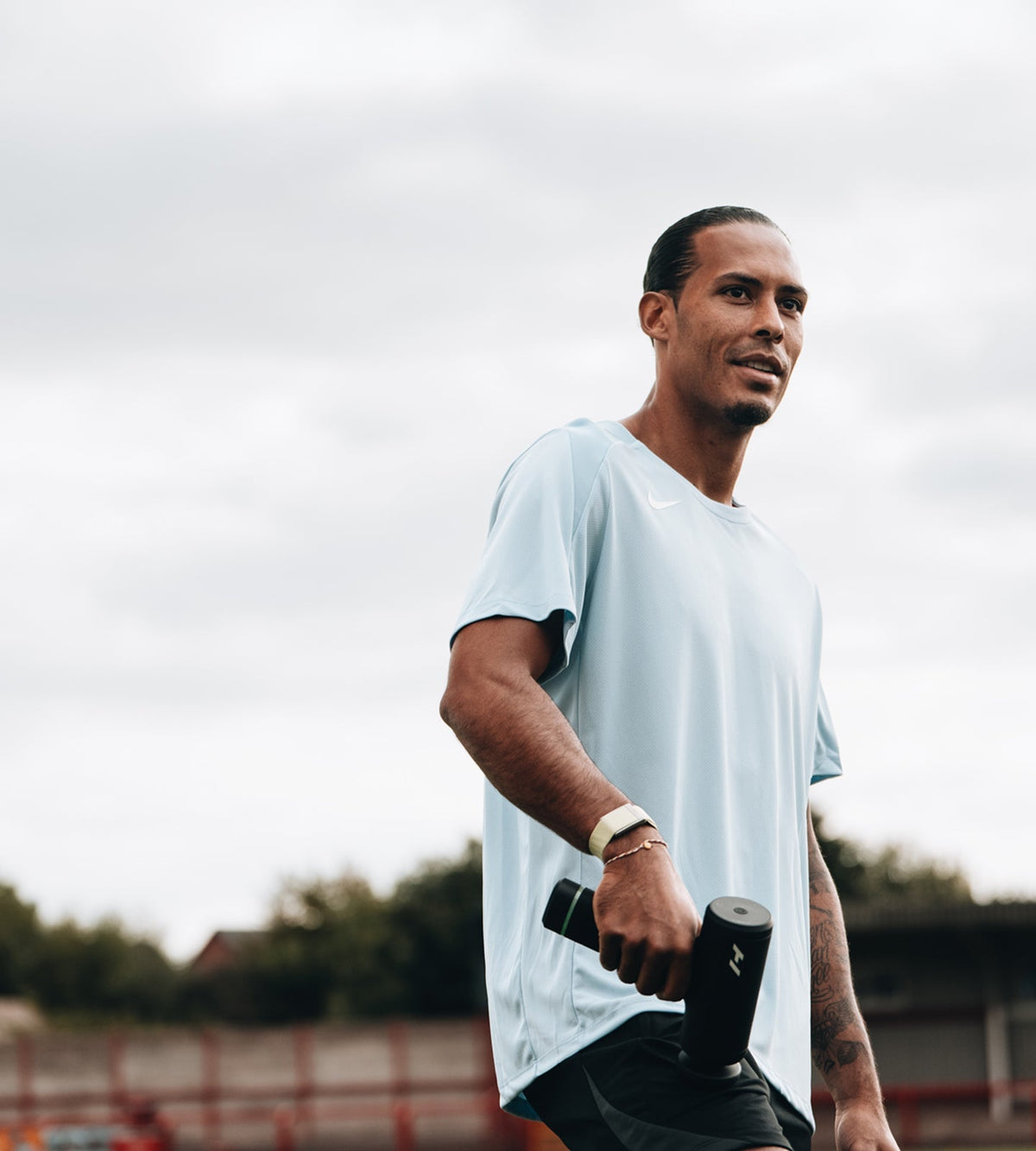 pro footballer virgil van dijk using a hypervolt on his quad, outdoors.