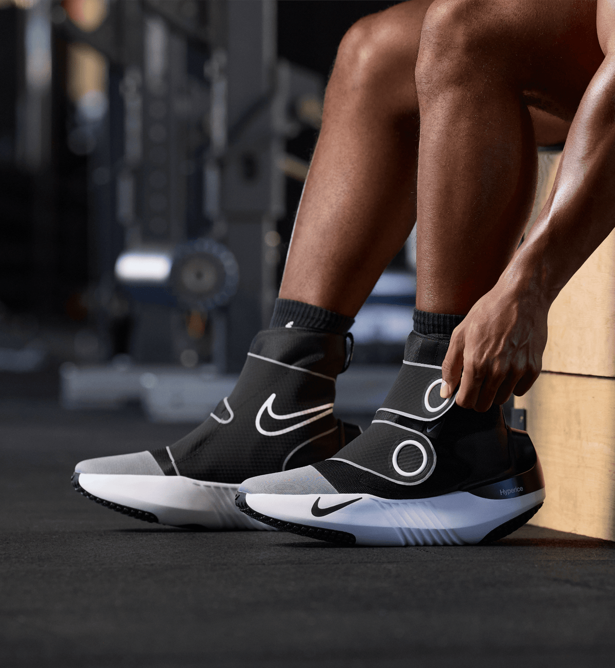Persoon trekt de Hyperboot by Nike × Hyperice aan in de sportschool