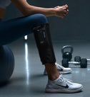 Personne assise en salle de sport avec les Normatec Lower Legs